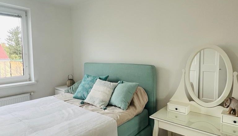 Schlafzimmer, © Martina Lechner Schlafzimmer mit einem Bett, Kissen und einem Schminktisch mit Spiegel.