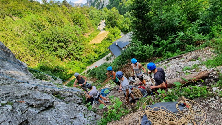 Kletter-Yoga-Camp im Höllental, © Raufgeklettert - Petra Weisz Gruppe von Kletterern mit Helmen an einem Felsen im Wald.