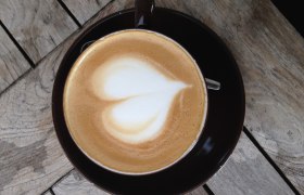 Gemütlich und chic Kaffee genießen, © gemeinfrei Eine Tasse Cappuccino mit Herz-Latte-Art auf einem Holztisch.