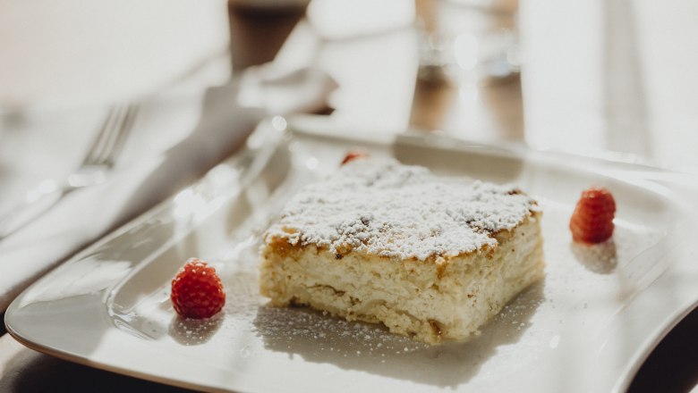 Milk cream strudel, © Niederösterreich Werbung/Sophie Menegaldo A piece of milk cream strudel with powdered sugar and raspberries on a white plate.