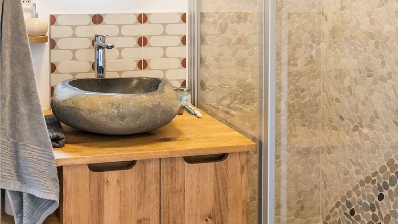 Badezimmer Ronja, © WW Wohnwagon GmbH Modernes Badezimmer mit Natursteinwaschbecken und Holzschrank.