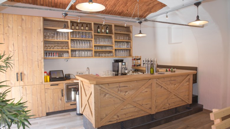 Parlor, © Christian Piribauer Wooden bar with glasses and bottles and brick ceiling.