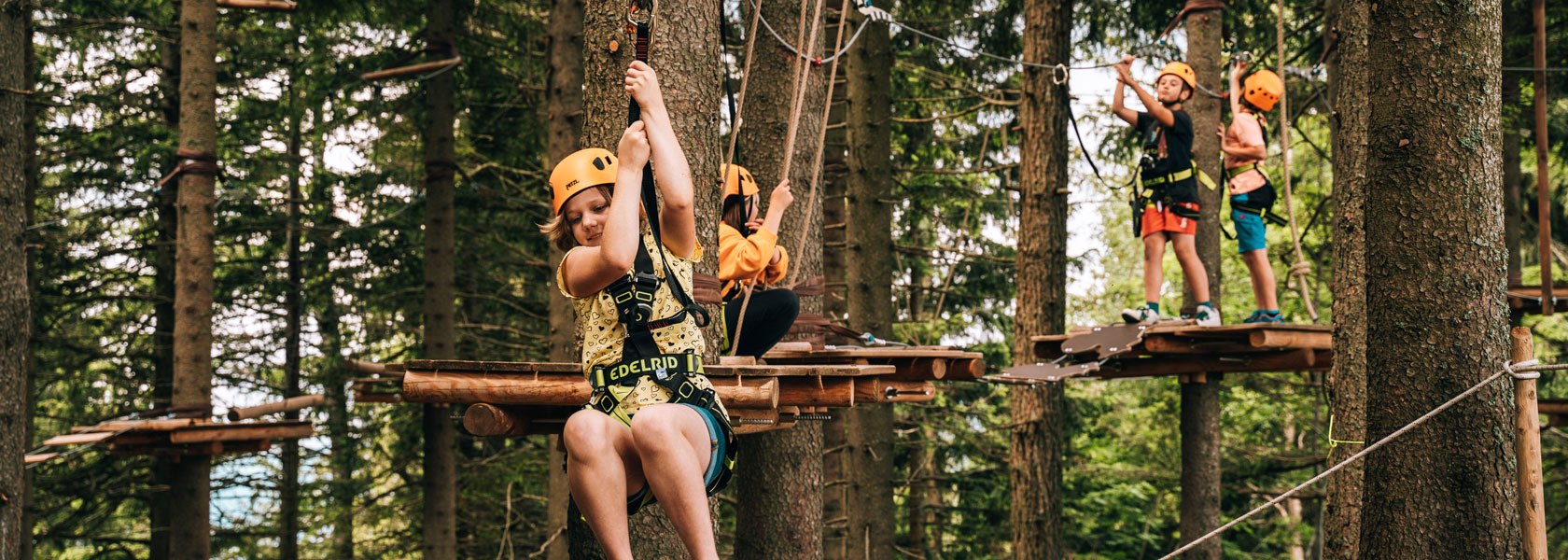 Schüler:innengruppe im Waldseilgarten Hirschenkogel Semmering, © Semmering Hirschenkogel Vier Schüler:innen klettern munter durch den Waldseilgarten