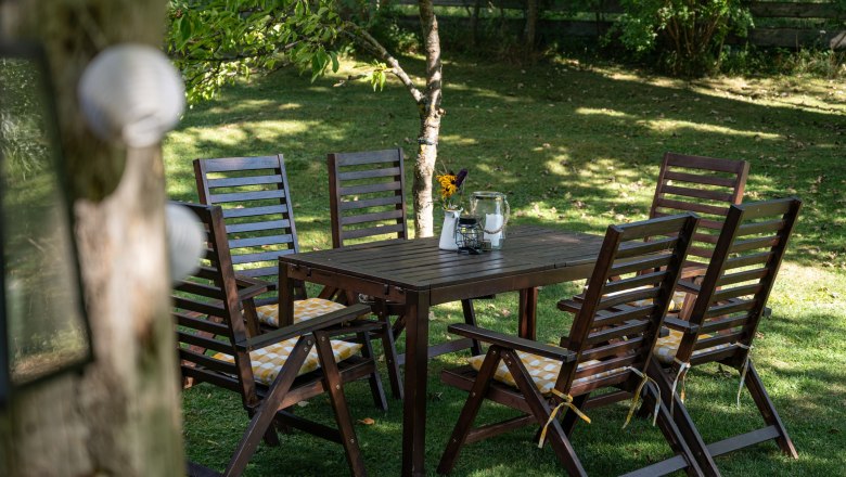 Garten, Ferienhaus Schlager, © Claudia Schlager Garten mit Holztisch und Stühlen, dekoriert mit Blumen und Kerzen.