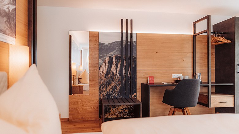 Premium Doppelzimmer mit Balkon, © Payerbacherhof - Christopher Tarkus Modernes Hotelzimmer mit Holzverkleidung, Schreibtisch und Stuhl.