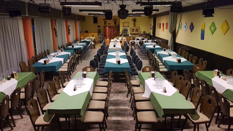 Wirtshausbühne Bernhart, © Wirtshausbühne Bernhart Ein großer Saal mit langen, gedeckten Tischen und Stühlen, bereit für eine Veranstaltung.