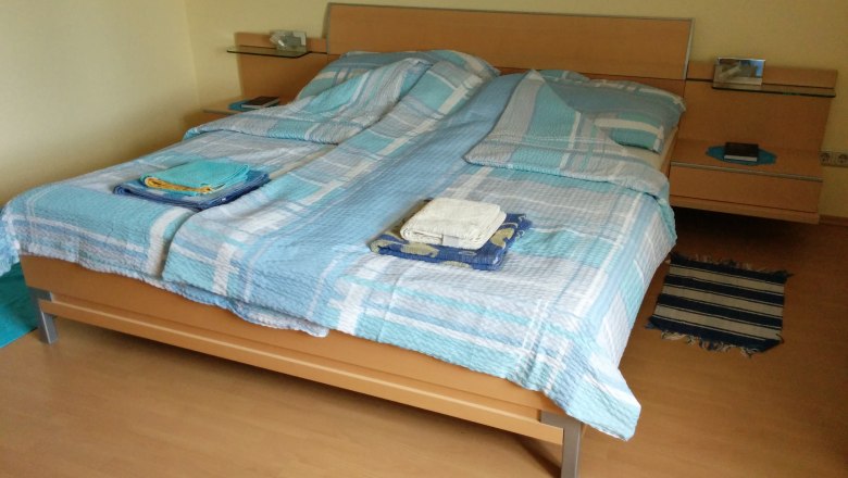 Doppelbett im Buchenzimmer, © Reep Doppelbett mit blauer Bettwäsche in einem Zimmer mit Holzboden.