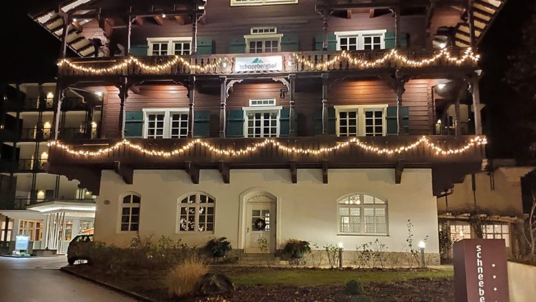 Schneeberghof im Winter, © Hotel Schneeberghof Ein beleuchtetes Gebäude im traditionellen Stil bei Nacht, mit Lichterketten geschmückt.