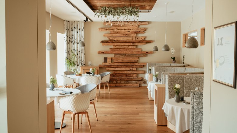 Haubenrestaurant Gaumenkitzel, © Heldentheater Innenansicht eines eleganten Restaurants mit Holzboden, modernen Möbeln und dekorativen Holzelementen an der Wand.