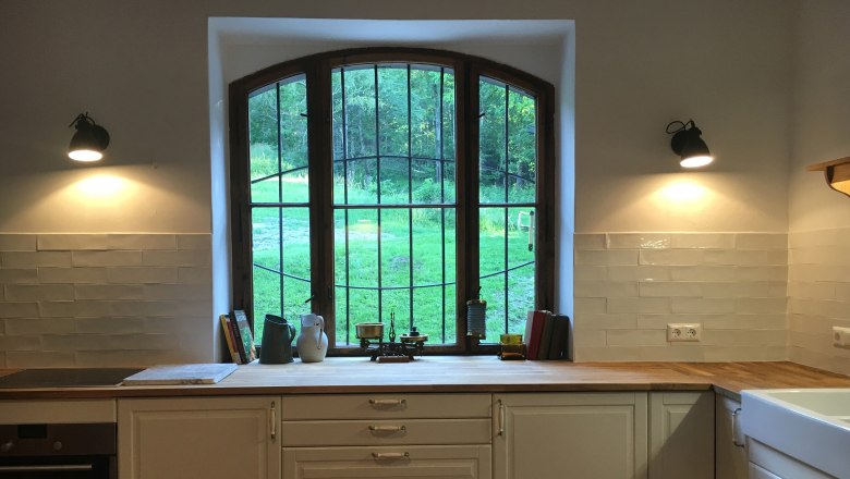 Kitchen, © Riegelhof Kitchen with large window, wooden worktop and white cupboards.
