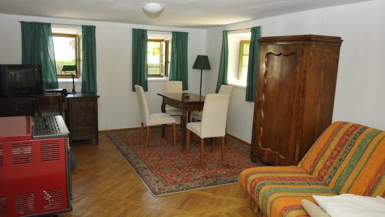 Gästehaus 3, © fritz fischer Gemütliches Gästezimmer mit Holzmöbeln, Teppich und Sofa.