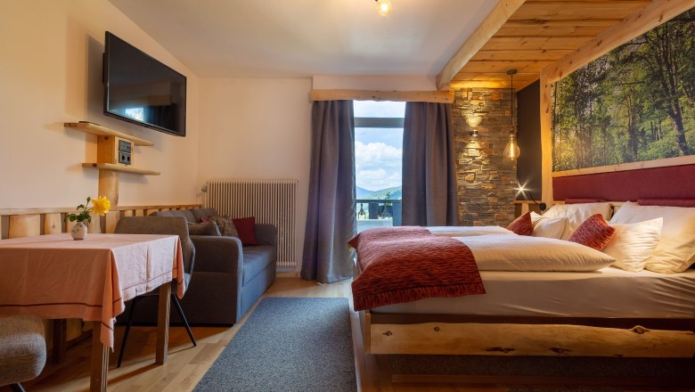 Land-Pension Kaiserhof, © Scharfegger´s Raxalpen Resort Gemütliches Hotelzimmer mit Doppelbett, Sofa, Tisch und großem Fenster mit Bergblick.