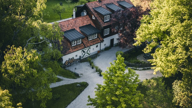 Landsitz Oberhof, © Niederösterreich Werbung / Maximilian Pawlikowsky Luftaufnahme eines traditionellen Hauses im Grünen, umgeben von Bäumen und einem gepflegten Garten.