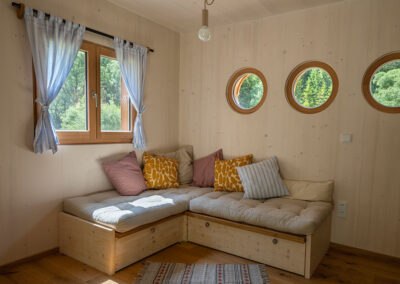 Huberto modular house, © Carina Rebler Cozy sitting area in a wooden modular house with round windows.