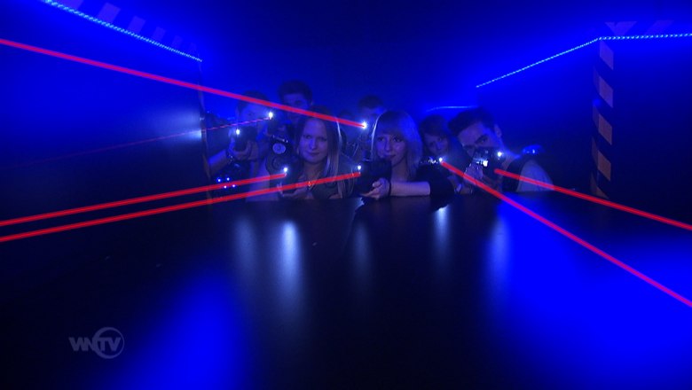 Lasertag, © Suracon OG Menschen spielen Lasertag in einem dunklen Raum mit blauen Lichtern und roten Laserstrahlen.