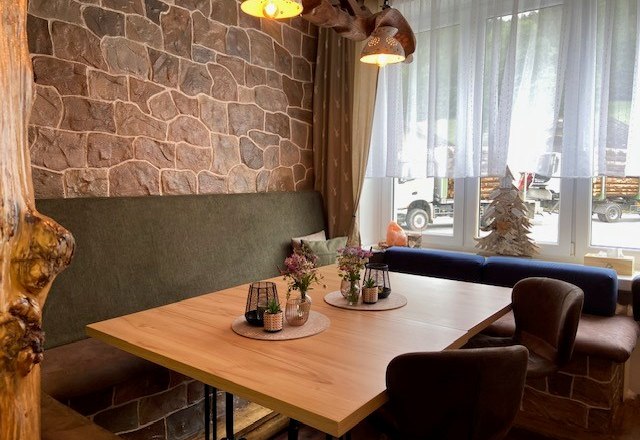 Gemütliche Sitzgelegenheit Hofladen, © Wiener Alpen Gemütliche Sitzecke in einem Hofladen mit Holztisch, gepolsterten Stühlen und Dekorationen auf dem Tisch.