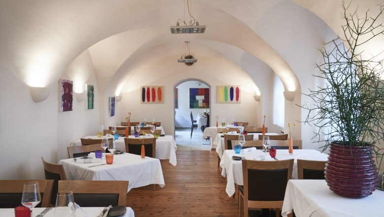 Medieval vault, timeless ambience, © Niederösterreich Werbung/Andreas Hofer An elegant restaurant with a vaulted ceiling, white tablecloths and colorful decorations.