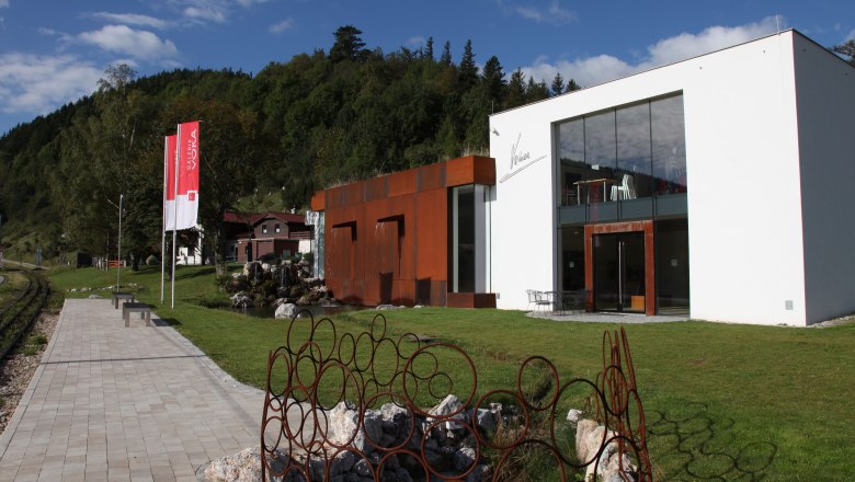 Galerie & Atelier VOKA in Puchberg am Schneeberg, © Voka Moderne Galerie mit Glasfassade und rostigen Metallskulpturen im Grünen.