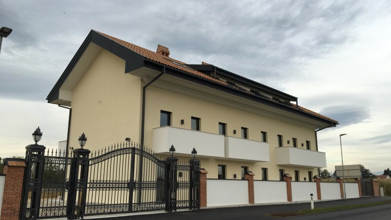 Außenansicht, © Mattone GmbH Außenansicht eines modernen Gebäudes mit Ziegeldach und schmiedeeisernem Tor.