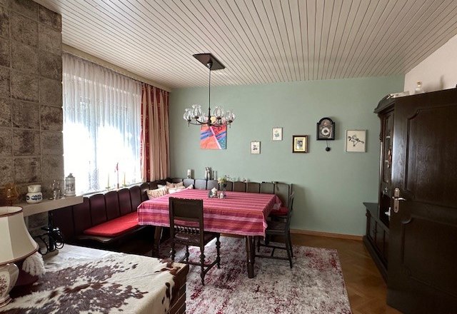 Wohnzimmer, © Heidi Peer Gemütliches Wohnzimmer mit Esstisch, Eckbank, Teppich und Wanduhr.