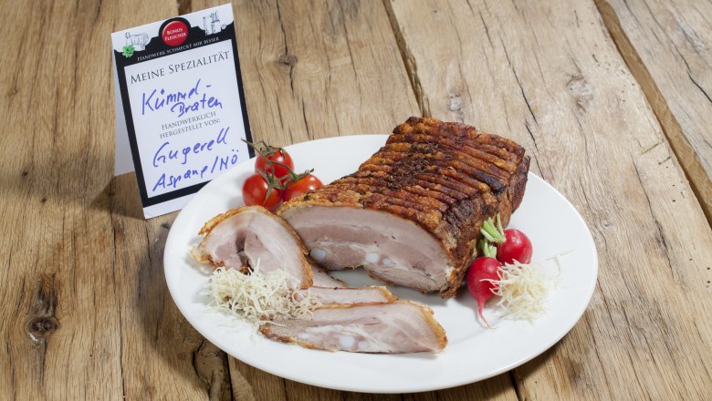 Butcher's Gugerell, © Bonusfleischer A plate of caraway roast, radishes and tomatoes on a wooden table.