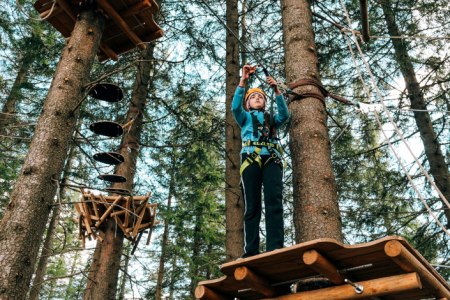 Waldseilgarten Hirschenkogel Semmering, © Semmering-Hirschenkogel Person im Kletterpark auf Plattform zwischen Bäumen.