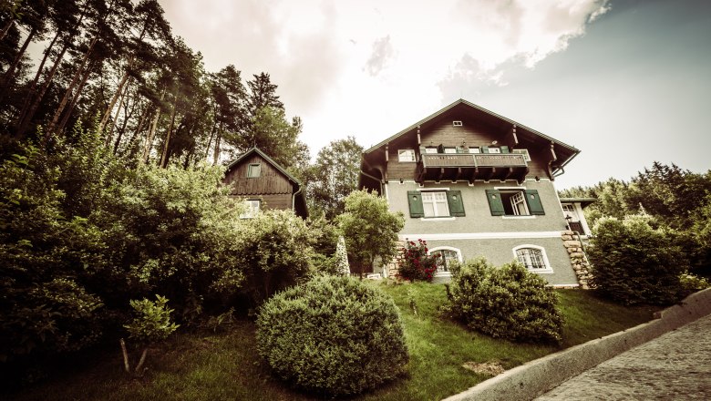 Villa Antoinette, © Matthias Kronfuss Eine Villa mit grünem Garten und Bäumen im Hintergrund.
