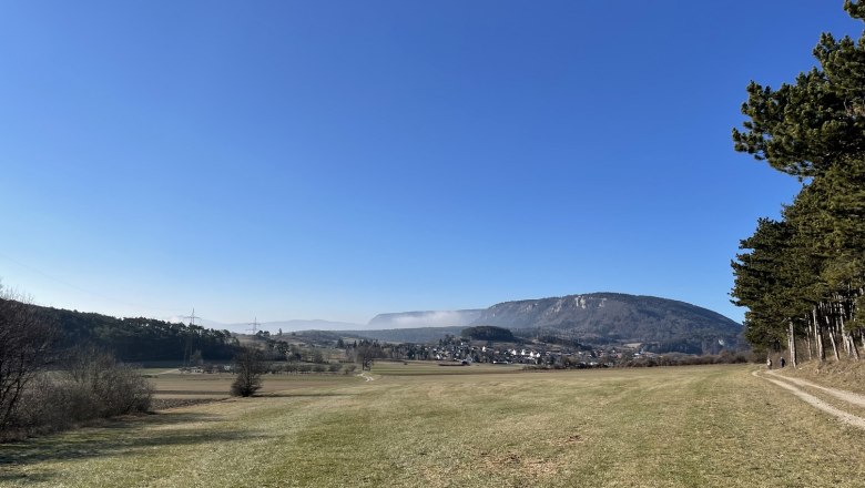 Blickplatz Rotes Kreuz, © Wiener Alpen/Katharina Lechner Landschaft mit Wiese, Hügeln und klarem Himmel.