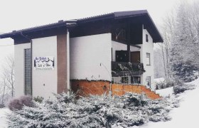 Winterstimmung, © Familie Weibels Ein verschneites Gebäude mit einem Schild 'Bei Webels Ski & Bike Zimmer-Apartments'.