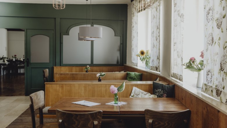 Traditionelles Wirtshaus, kreative Küche, © Niederösterreich-Werbung/Sophie Menegaldo Innenansicht eines traditionellen Wirtshauses mit Holzmöbeln und Blumen auf den Tischen.