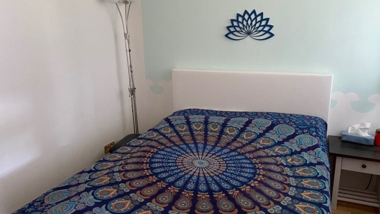 Ein Schlafzimmer mit Wasserbett, © Wiener Alpen Schlafzimmer mit Wasserbett, bunter Bettdecke und Lotus-Wanddekoration.