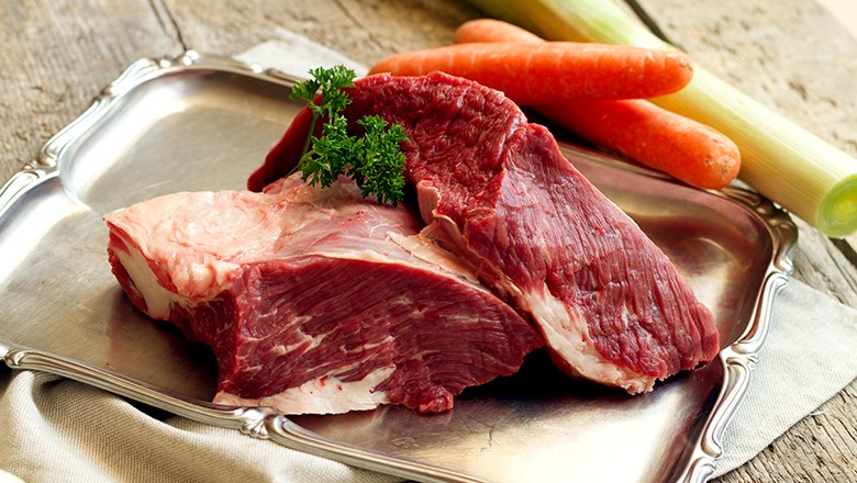 Fresh meat, © Sooo gut schmeckt die Bucklige Welt/ Viktoria Kornfeld Two pieces of raw meat on a silver tray on a wooden table. Next to it, carrots and leeks.