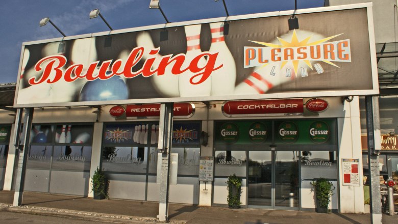Pleasureland, © Wiener Alpen/Katrin Zeleny Eingang zu einem Bowlingcenter namens Pleasureland mit großen Schildern und Logos.