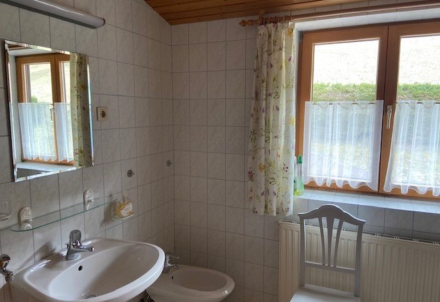 Bathroom, © Wiener Alpen A bathroom with washbasin, bidet, mirror and window with curtains.