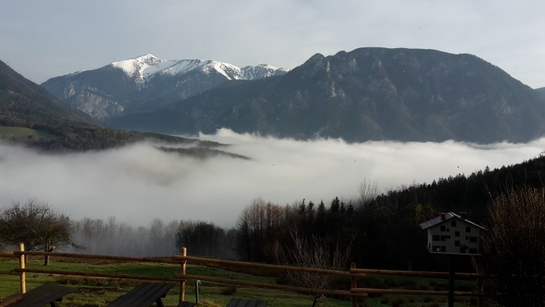BaBioL Reichenau, © BaBioL Blick auf schneebedeckte Berge über einem Tal mit Nebel und einem Holzzaun im Vordergrund.