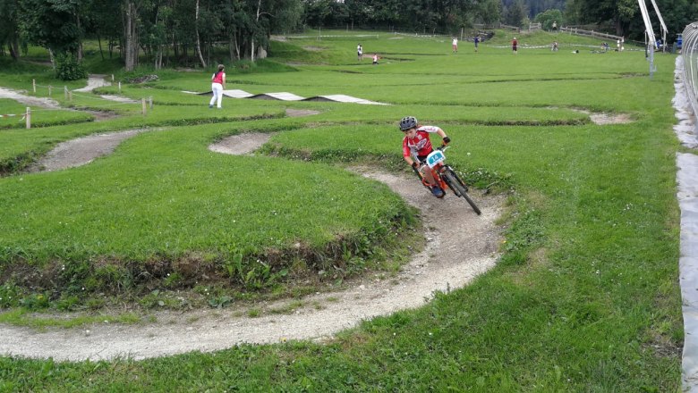 ...der nahegelegene Minibike Park der Wexl Trails, © Familie Rosinger Kind fährt auf einem Minibike-Parkour im Grünen.
