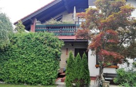 Außenansicht, © Pension Kubicek Außenansicht eines Hauses mit Balkon, umgeben von Bäumen und Sträuchern.