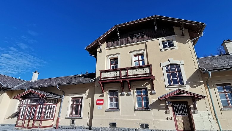 Bahnhof Ausschlag-Zöbern, © Wiener Alpen, intern Historisches Bahnhofsgebäude mit gelber Fassade und rotem Holzdekor unter blauem Himmel.