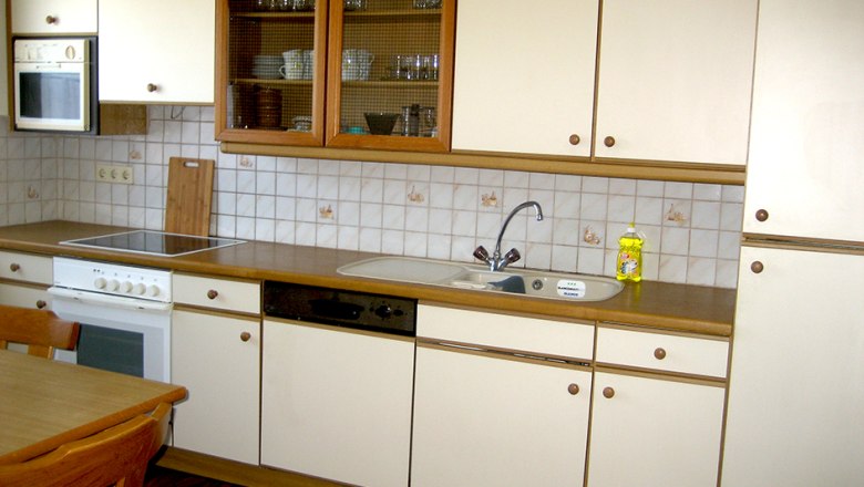 Kitchen, © Anke Spreitzer Kitchenette with white cupboards, stove, sink and dishwasher.