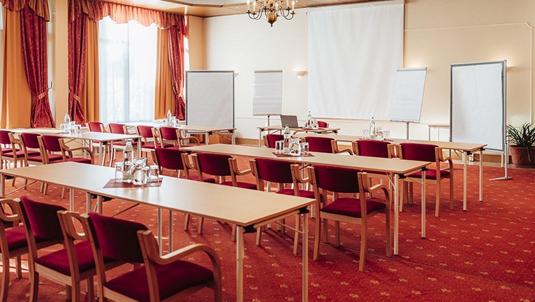 Seminarraum, © Payerbacherhof - Christopher Tarkus Ein Seminarraum mit roten Stühlen, Tischen, Flipcharts und einem Projektor.