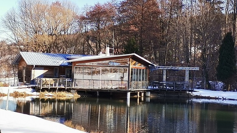 Restaurant and fish farm Wechselforelle, © Wiener Alpen, intern A restaurant on the banks of a pond in winter, surrounded by trees.