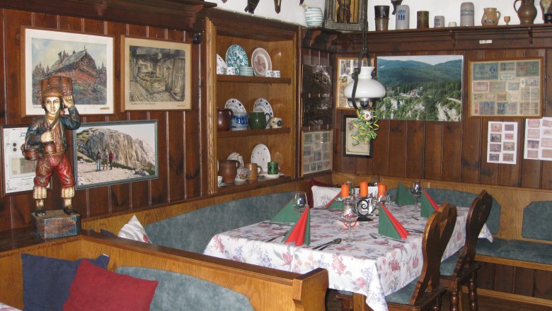 The restaurant in the Kohlröserlhaus, © Susanne Czerny Rustic dining room with wooden furniture, wall decorations and table setting.
