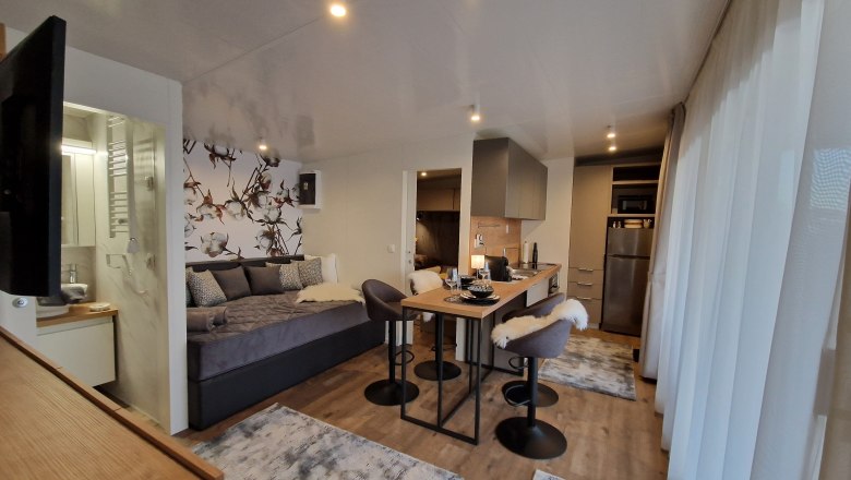 Wohnzimmer Johannesbachklamm Chalet, © Johannesbachklamm Chalet Modernes Wohnzimmer mit Küchenzeile, Esstisch und Sofa.