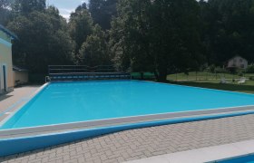 foto-bad-7, © Gemeinde Gutenstein Ein leerer Swimmingpool im Freien, umgeben von Bäumen und einem Gebäude.