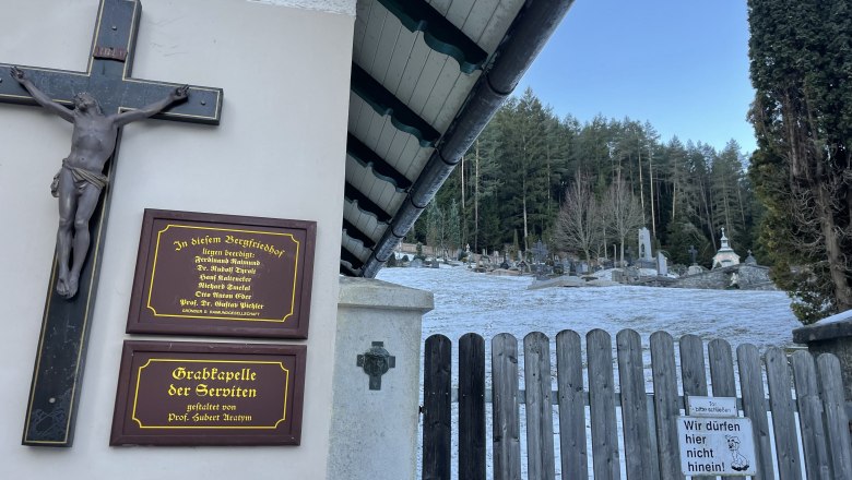 Bergfriedhof Gutenstein, © Wiener Alpen/Katharina Lechner Eingang zum Bergfriedhof Gutenstein mit Holztor, Kreuz und Gedenktafeln. Im Hintergrund sind Gräber und Bäume zu sehen.
