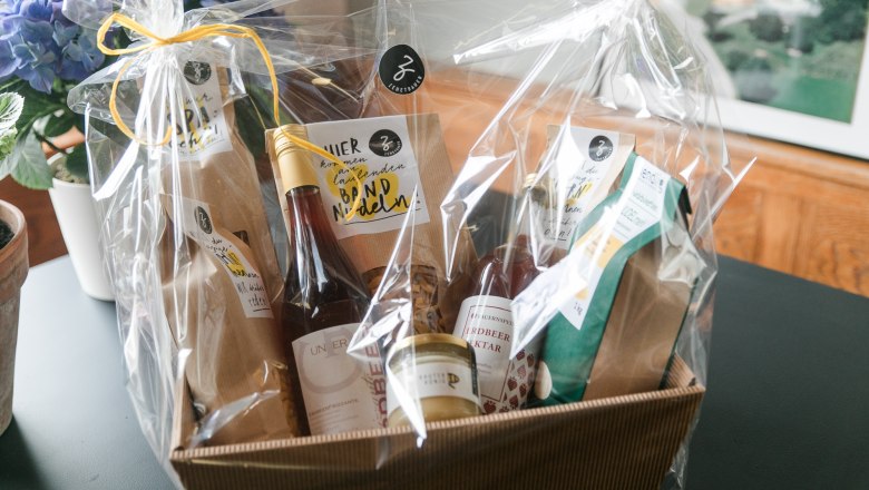 Hofladen beim Feriennest Zehetbauer, © heiter-weiter.at/Karl Stangl Geschenkkorb mit regionalen Produkten, verpackt in Folie, auf einem Tisch.