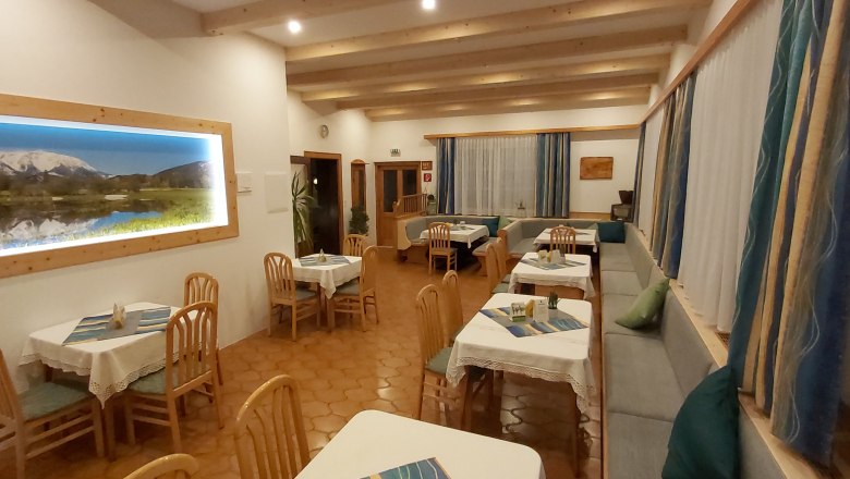 Stüberl, © Martin Zwinz Gemütliches Restaurant mit Holzmöbeln und Bergbild an der Wand.