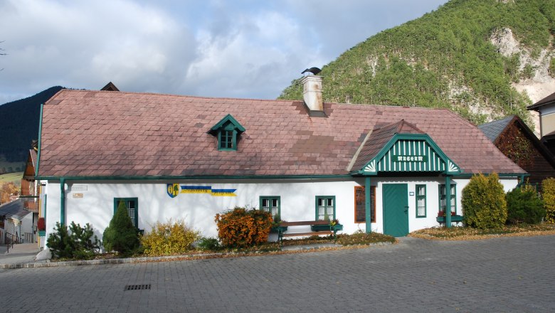 Schneeberg Museum Puchberg, © Schneebergmuseum Schneeberg Museum Puchberg, a traditional building with a green roof and chimney, surrounded by mountains and trees.