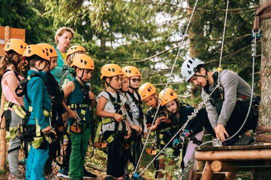 Klettern im Waldseilgarten Hirschenkogel Semmering, © Semmering Hirschenkogel Ein Gruppe an Kindern mit Kletterausrüstung passt auf, was ihnen von dem Kletter-Leher erklärt wird