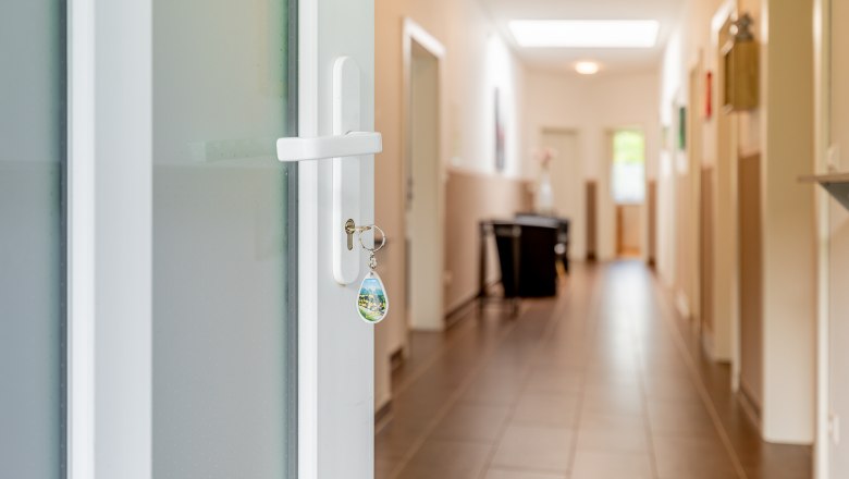 Ferienwohnung Semler, © Wiener Alpen / Christian Kremsl Ein Schlüssel steckt in einer weißen Tür, die zu einem hellen Flur mit Fliesenboden führt.